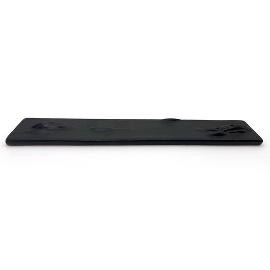 Flat side view of minimalistic black ceramic incense holder with mountain ridges