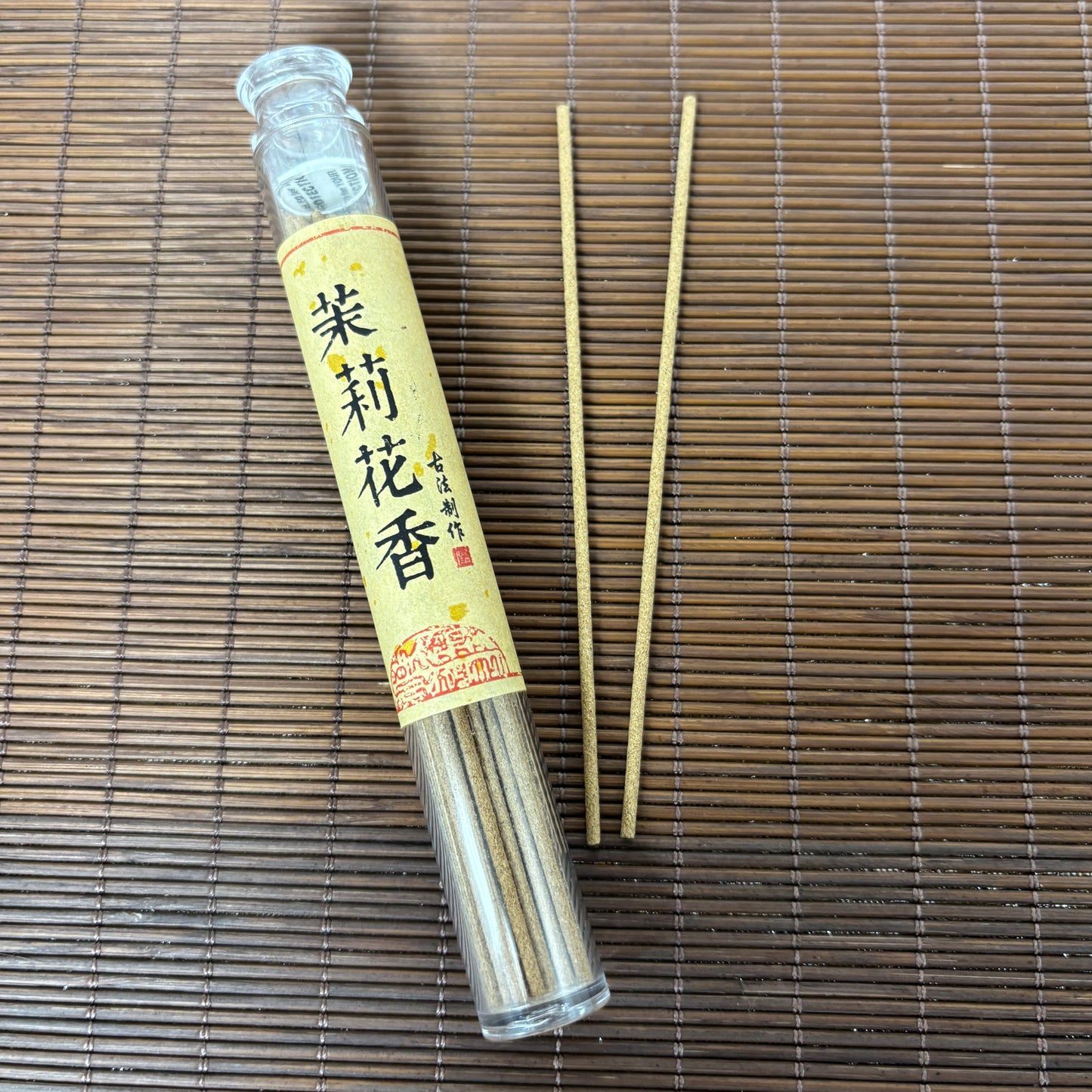 Jasmine Blossom incense in clear plastic tube with white floral short sticks on bamboo mat