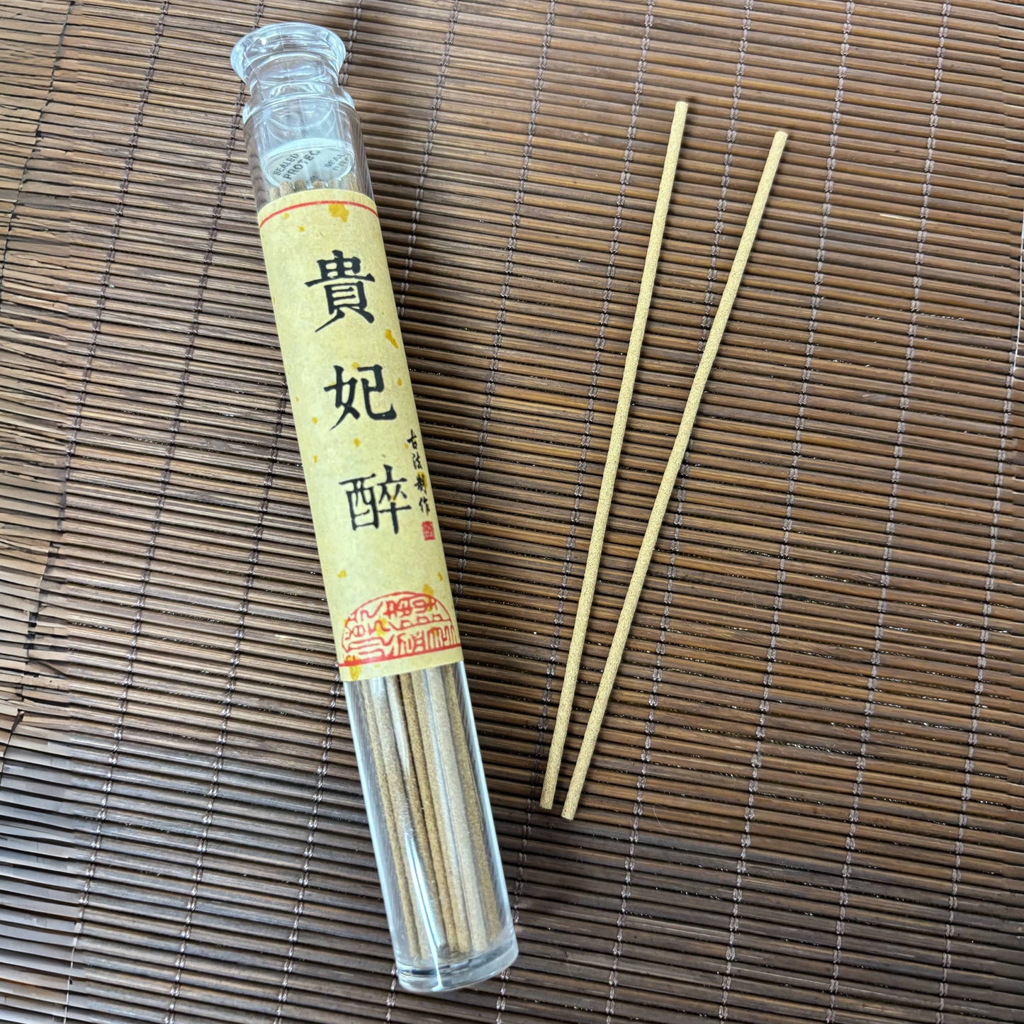 Lychee Mist incense sticks in a clear plastic tube, with two sticks displayed on a bamboo mat