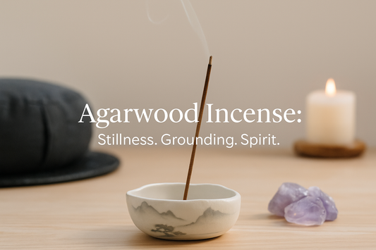 Agarwood incense stick burning in a ceramic holder with amethyst crystals and a candle, creating a calm meditation atmosphere
