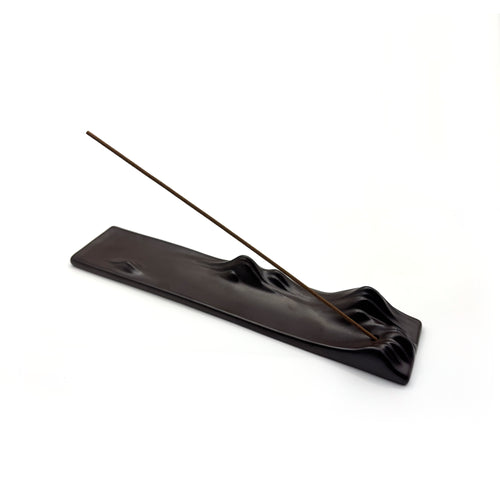 Angled view of black ceramic incense holder with single hole and mountain-shaped design